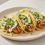 Ancho chicken tacos with corn tortillas, browned chicken, cabbage, cilantro, avocado, and lime