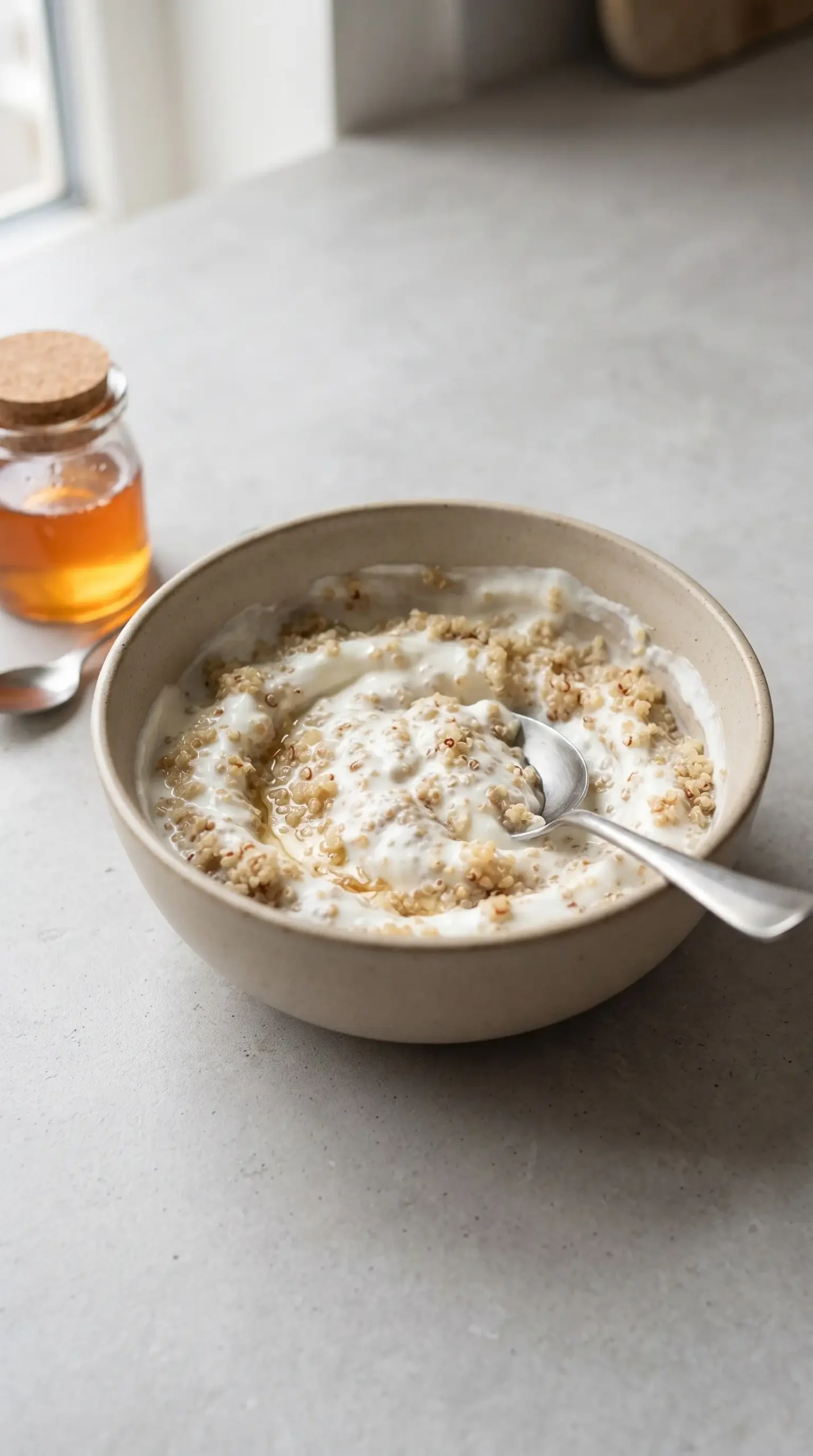 Greek yogurt mixed with cooked quinoa and honey in a bowl