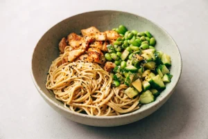 Sesame noodle bowl with chicken, edamame, cucumber, and creamy sesame sauce